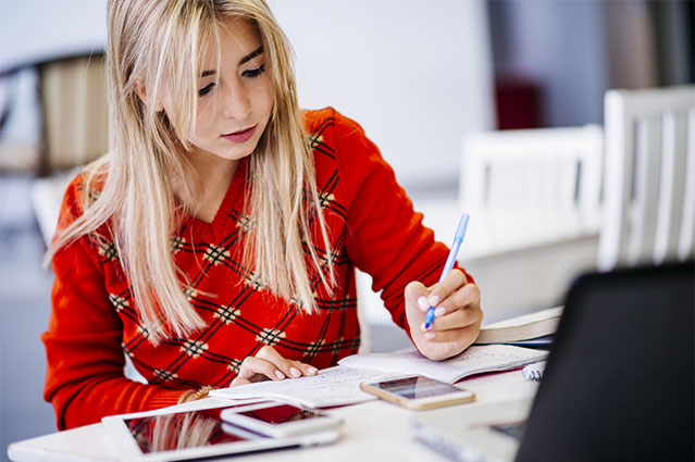 woman wearing red shirt writing on her notebook