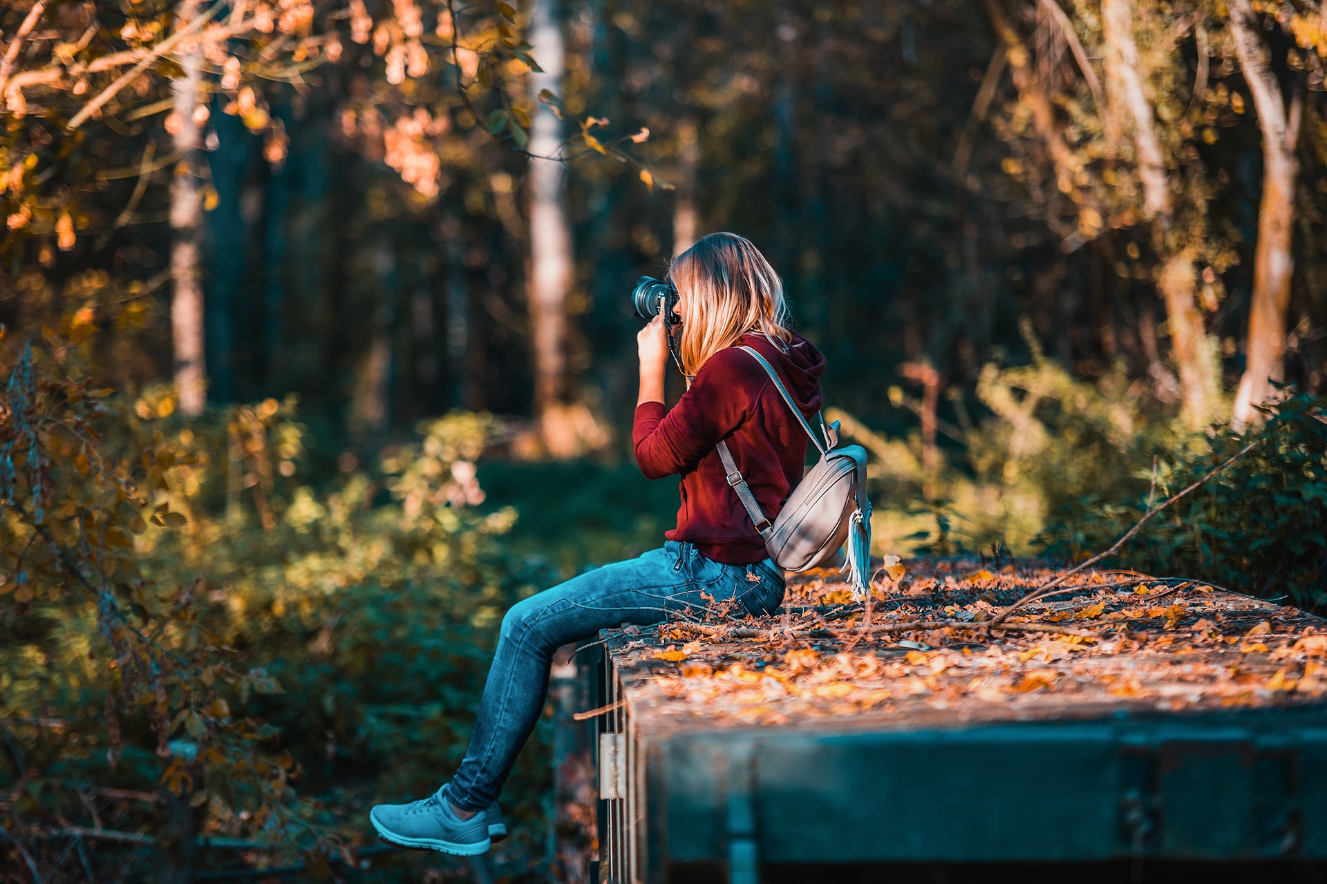 woman wearing red shirt taking photos on the woods